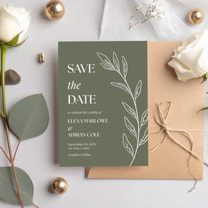 Może przedstawiać: Karta zaproszenia ślubnego z napisem "SAVE the DATE" w kolorze białym na zielonym tle. Karta posiada biały kwiatowy wzór i jest ozdobiona brązową kopertą, białymi różami i złotymi elementami dekoracyjnymi.