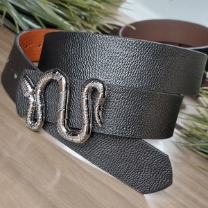 May include: A black leather belt with a silver snake buckle. The belt is folded in half and the buckle is in the centre of the image.