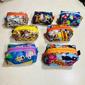 May include: A collection of eight colorful zippered pouches with various cartoon character designs. The pouches are made of fabric and have a zipper closure. The designs include characters from popular TV shows and movies.