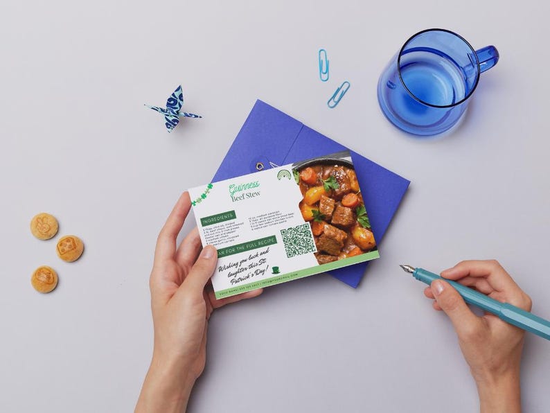 Pode incluir: Um cart&atilde;o de receita verde e branco com uma imagem de ensopado de carne Guinness. O cart&atilde;o tem o t&iacute;tulo "Guinness Beef Stew" e inclui um c&oacute;digo QR. O cart&atilde;o est&aacute; sobre um envelope azul com fundo branco.
