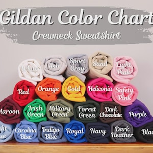 May include: A color chart for Gildan crewneck sweatshirts, displaying a variety of rolled fabric samples. Colors include white, ash, sport gray, sand, light pink, red, orange, gold, heliconia, safety pink, maroon, Irish green, military green, forest green, dark chocolate, purple, light blue, carolina blue, indigo blue, royal, navy, dark heather, and black.
