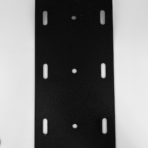 May include: Black metal plate with six evenly spaced holes, four rectangular and two round.