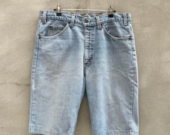 May include: Light blue denim shorts hanging on a hanger against a gray textured wall.