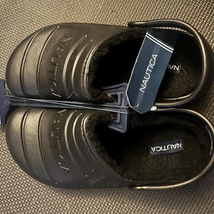 May include: A pair of black Nautica slip-on clogs with a fuzzy lining. The clogs have a rubber sole and the brand name is printed on the side.