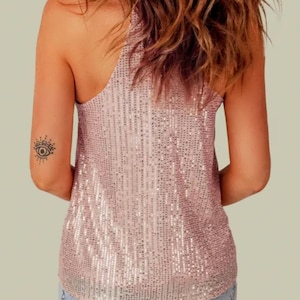 May include: A pink sequined tank top with a scoop neck and a relaxed fit. The tank top is made of a soft, comfortable fabric and has a subtle shimmer.