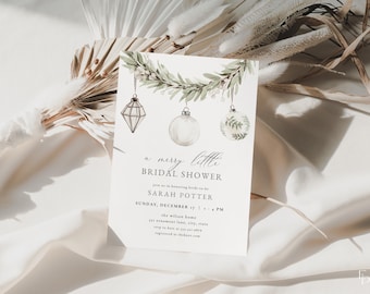 May include: A white invitation card for a bridal shower with the text "a merry little BRIDAL SHOWER". The card features watercolor illustrations of hanging ornaments and a garland. The card is on a white fabric background.