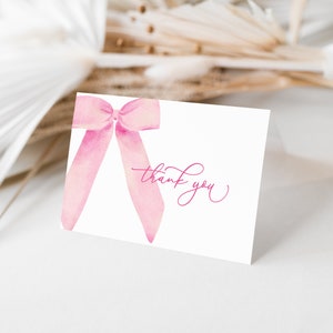 May include: A white thank you card with a pink watercolor bow. The text "thank you" is written in pink cursive.