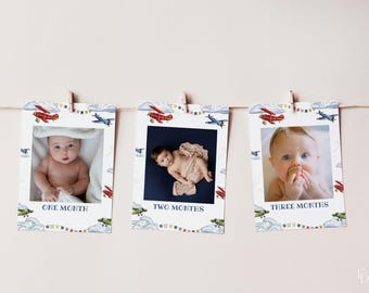 May include: A set of three baby milestone photo cards hanging from a string. Each card features a baby photo and is decorated with watercolor airplanes, clouds, and the text "ONE MONTH", "TWO MONTHS", and "THREE MONTHS".