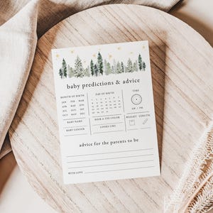 May include: A white card with a forest green watercolor background and gold stars. The card has the text "baby predictions & advice" and includes sections for guests to predict the baby's birth month, day, time, name, gender, hair and eye color, and weight and length. There is also a section for advice for the parents to be.
