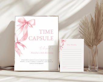 May include: A pink and white time capsule sign with a pink bow and the text "TIME CAPSULE to be opened on Natalia's 18th Birthday". A white card with a pink bow and the text "Dear Natalia," is next to the sign.