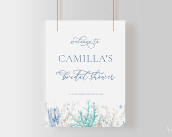 May include: A white sign with blue text that says "Welcome to Camilla's bridal shower 43 days until she says I do". The sign is decorated with watercolor illustrations of coral, seashells, and starfish.