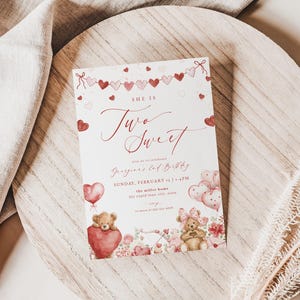 May include: A birthday invitation with the text "She is Two Sweet" in elegant script. The design features red hearts, teddy bears, and balloons. The invitation is on a white background, with event details below.