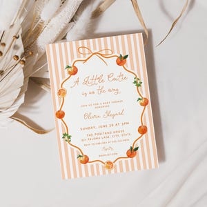 May include: A baby shower invitation with a peach and white striped background. The text "A Little Cutie is on the way" is written in elegant script, surrounded by a wreath of oranges and greenery. The invitation includes details for the event.