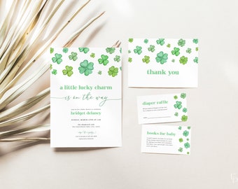 Op de afbeelding: Een baby shower uitnodiging met een groen klavertjevier patroon. De uitnodiging luidt "een klein geluksbrenger is onderweg" en bevat de naam "Bridget Delaney". Er zijn ook kaarten voor een luiers loterij en boeken voor de baby.