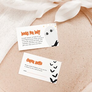 May include: Two white cards with orange and black text. The top card says "books for baby" and has a ghost illustration. The bottom card says "diaper raffle" and has bat illustrations.