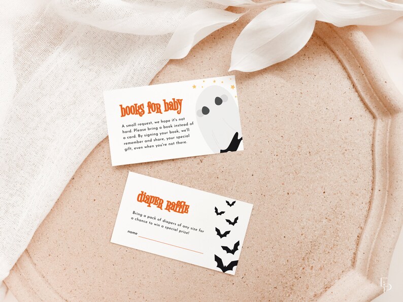 May include: Two white cards with orange and black text. The top card says "books for baby" and has a ghost illustration. The bottom card says "diaper raffle" and has bat illustrations.