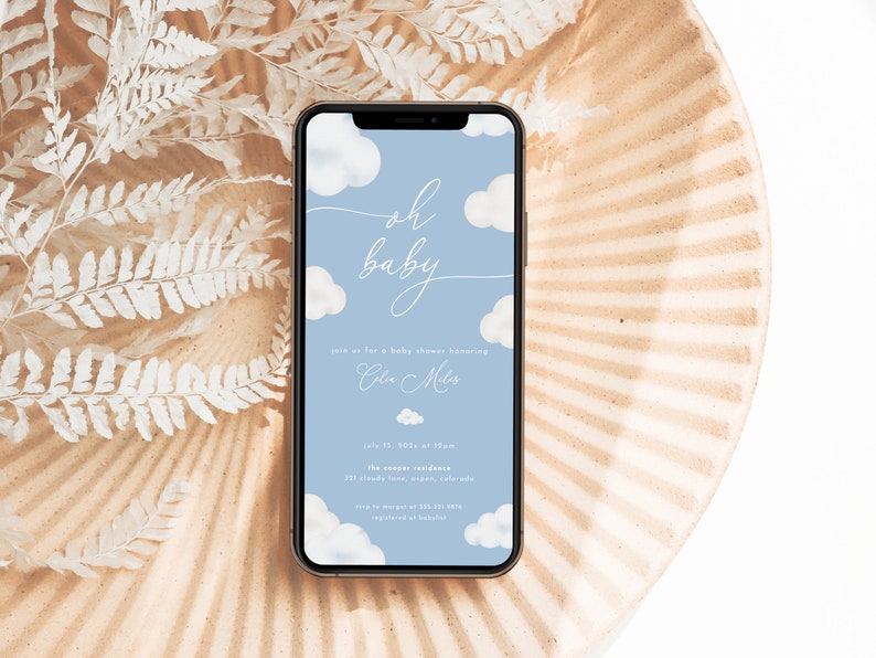 Pode incluir: Um convite para um ch&aacute; de beb&ecirc; azul e branco na tela de um smartphone. O convite apresenta um design de nuvens e o texto "oh baby" em uma fonte de escrita. O convite inclui a data, a hora e o local do ch&aacute; de beb&ecirc;.