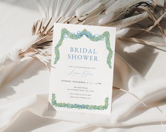 Könnte beinhalten: Eine weiße Karte mit grünem floralem Rand und einem blauen Schleifendesign. Der Text lautet "Bridal Shower" und "Feiern Sie mit uns die zukünftige Braut, Lauren Davis. Sonntag, 17. Dezember, 13:00 Uhr. Das Wool Bistro, 121 Main Lane, Stadt, Bundesstaat. RSVP an 123-456-7890. Registriert auf website.com"