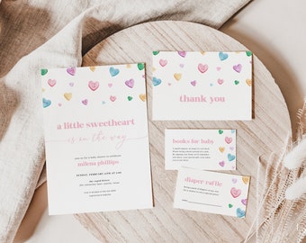 May include: A baby shower invitation with a pink and white background and a design of colorful candy hearts. The invitation says "a little sweetheart is on the way" and includes the name "milena phillips". There are also cards for books for baby and a diaper raffle.