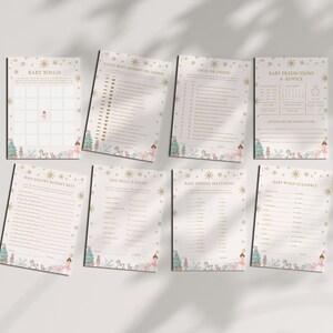 May include: A collection of baby shower game cards with a soft, neutral color palette. Each card features gold accents, illustrations of a ballerina, snowflakes, and Christmas trees. The games include Baby Bingo, Baby Predictions, and more.