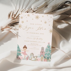 May include: A light beige invitation card with gold text and snowflake accents. The card reads "Our Little Sugar Plum Is Turning One" and features illustrations of a ballerina, a rocking horse, a nutcracker, and a Christmas tree.