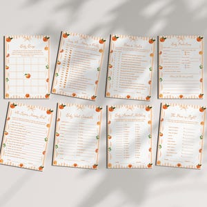 May include: A set of eight baby shower game cards. Each card features a peach and green leaf design with orange stripes. The cards have titles such as "Baby Bingo" and "The Price is Right".