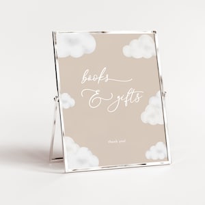 Puede incluir: Un cartel enmarcado en blanco con fondo beige y nubes blancas. El cartel dice "libros y regalos" con el texto "gracias" en la parte inferior.