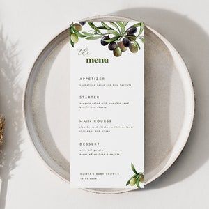 May include: A white menu card with a green olive branch illustration and the text "the menu". The menu lists appetizers, a starter, a main course, and dessert. The text at the bottom of the card reads "Olivia's Baby Shower".