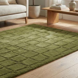 Puede incluir: Una alfombra verde con un patrón geométrico de diamantes. La alfombra está hecha de un material suave y afelpado y se coloca sobre un suelo de madera. La alfombra es de un color sólido y añade un toque de calidez y textura a la habitación.