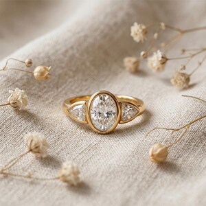 Luxury yellow gold engagement ring with oval cut diamond and modern bezel design.