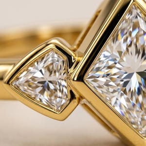 Modern bezel set engagement ring with 2 ct princess cut lab created diamond and three stone design.