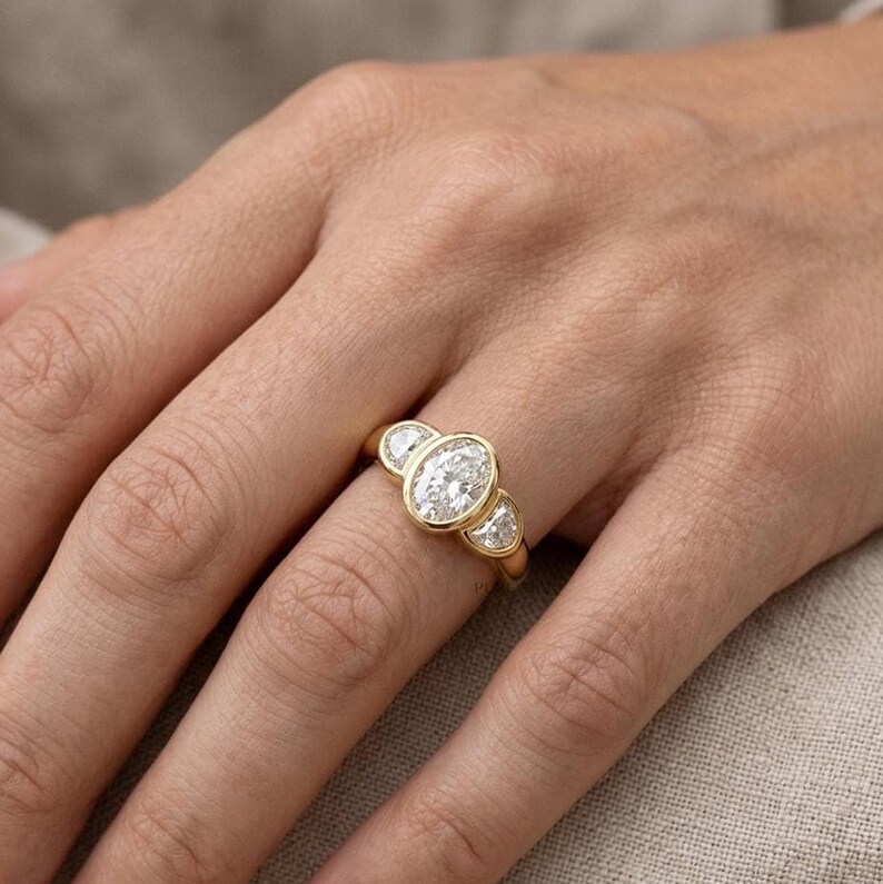 Elegant oval diamond trilogy ring featuring half moon side stones and sparkling lab grown diamonds.