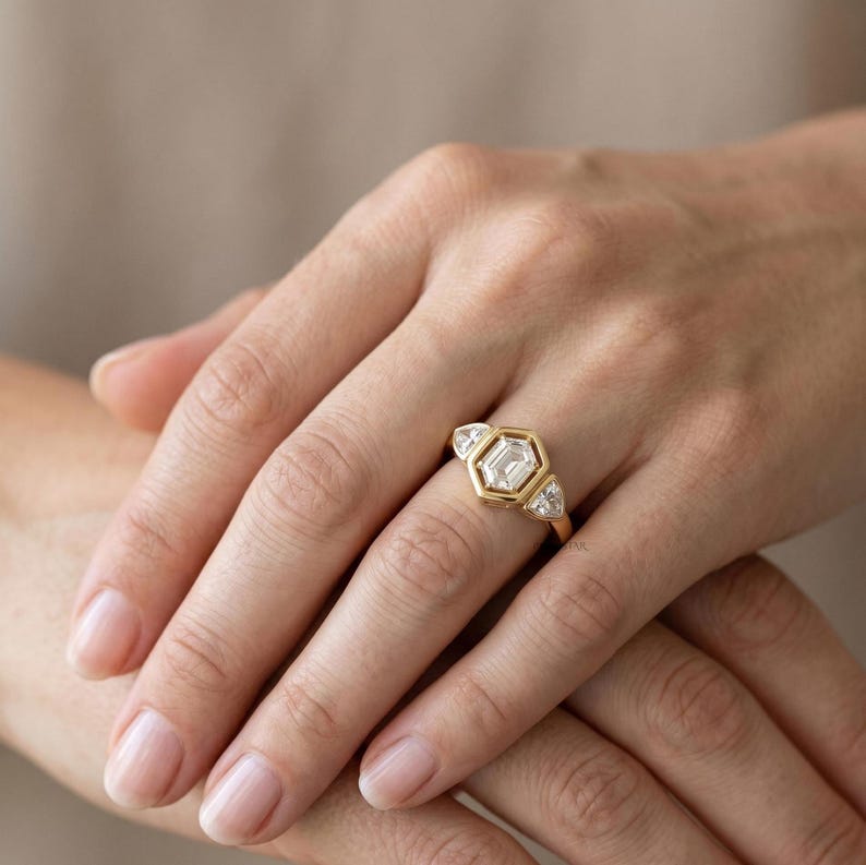 Unique lab grown diamond engagement ring with hexagon center stone and gold wedding band.