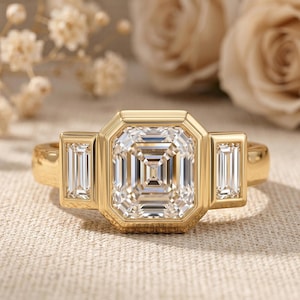 14K yellow gold Asscher cut lab grown diamond engagement ring with full bezel setting and side baguette diamonds.