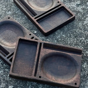 May include: Three wooden trays with different compartments and circular indentations. The trays are made of dark wood with a natural grain pattern.