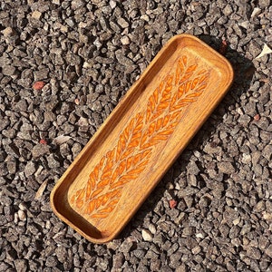 wooden catch all tray of 8 inch length has engraved resin patterns in the base clicked from a rock floor.