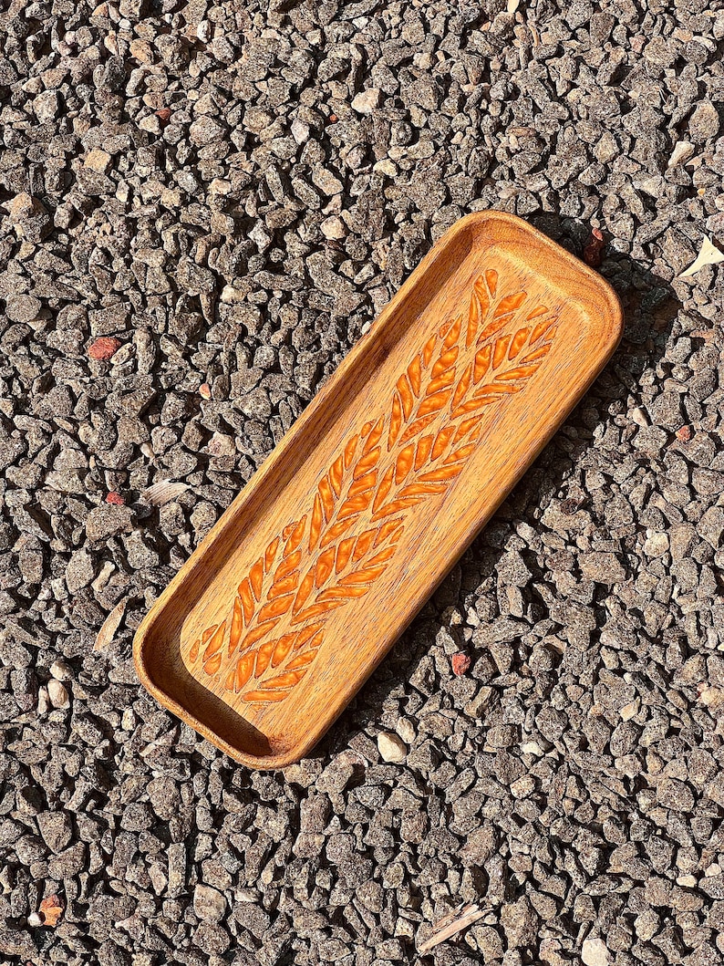 wooden catch all tray of 8 inch length has engraved resin patterns in the base clicked from a rock floor.