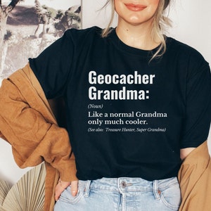 May include: Black t-shirt with white text that reads "Geocacher Grandma: (Noun) Like a normal Grandma only much cooler. (See also: Treasure Hunter, Super Grandma)"