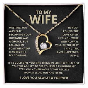 Puede incluir: Un collar con colgante en forma de corazón dorado con una gema redonda y transparente en el centro. El collar se muestra sobre un fondo negro con texto blanco que dice "TO MY WIFE" y un mensaje de amor.