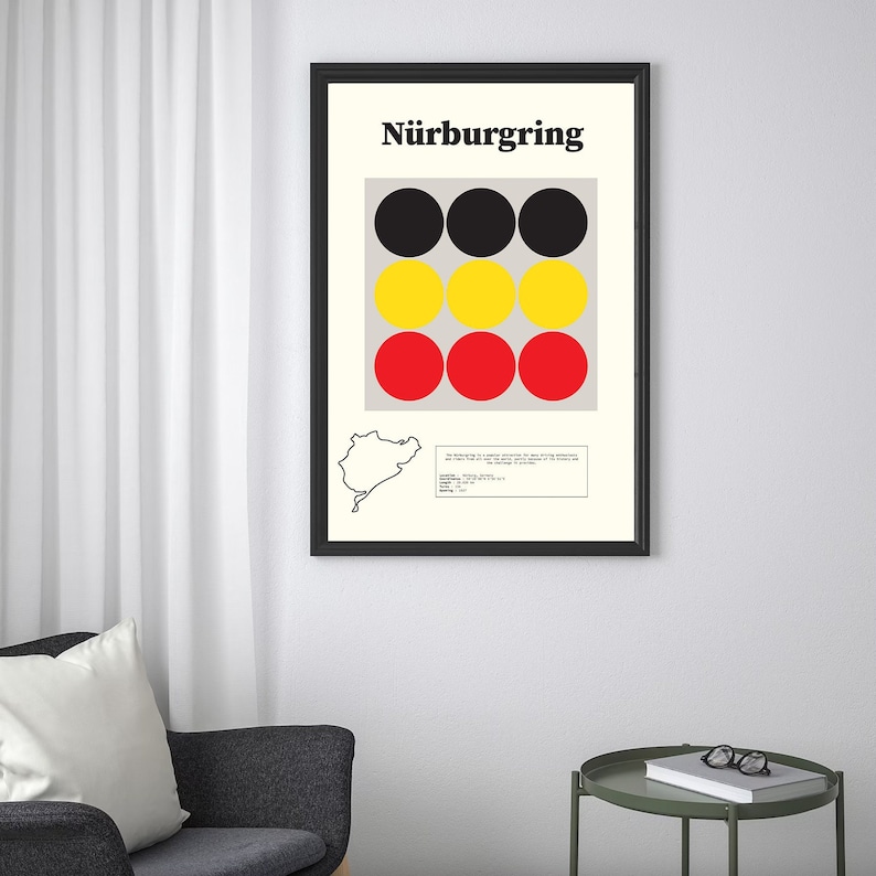 May include: A black framed poster with the word "N&uuml;rburgring" in bold white letters. The poster features a pattern of black, yellow, and red circles. A black and white outline of a racetrack is in the bottom left corner.