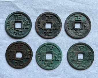 May include: Six antique Chinese coins with square holes in the center. The coins have a circular shape with visible inscriptions and a weathered, aged appearance, showing shades of green and brown.