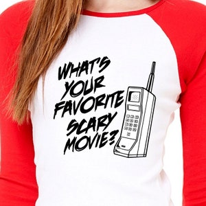 May include: A white and red baseball t-shirt with black text that reads "What's your favorite scary movie?" and a black and white illustration of a vintage rotary phone.
