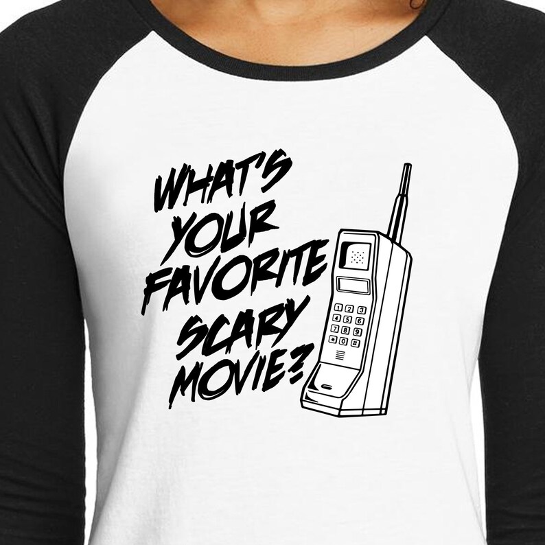 May include: A white and black baseball style shirt with a black and white graphic of a vintage cell phone and the text "What's your favorite scary movie?"