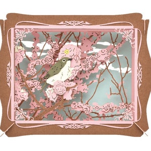 May include: A delicate papercraft scene featuring a small bird perched on a branch of a pink cherry blossom tree. The scene is framed in a brown and pink frame.