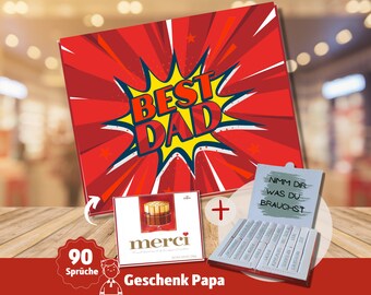 May include: A red and yellow gift box with the words "Best Dad" in a comic book style font. The box is open to reveal a white box with the words "Nimm dir was du brauchst" in black text. The box also includes a chocolate bar with the word "merci" on it. The box is on a wooden surface.
