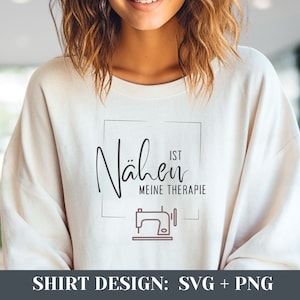 May include: A white t-shirt with a graphic design that says "Nähen ist meine Therapie" in a black square with a brown sewing machine icon inside.