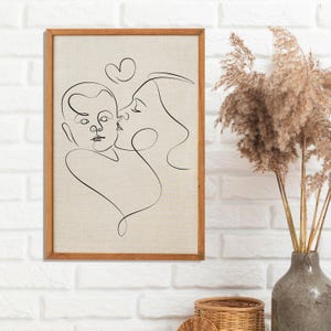 May include: A black and white line drawing of a mother and child embracing. The drawing is framed in a light brown wood frame and is hanging on a white brick wall.