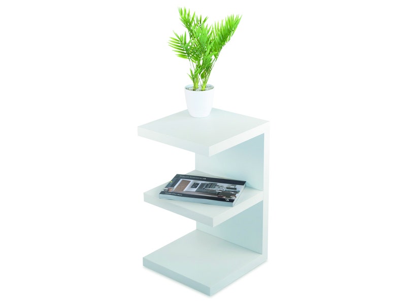 Puede incluir: Estanter&iacute;a blanca de tres niveles con una planta en una maceta blanca en el estante superior y un libro en el estante del medio.
