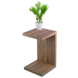 May include: A wooden C-shaped end table with a plant in a white pot on the top shelf.