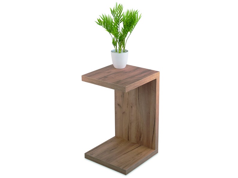 May include: A wooden C-shaped end table with a plant in a white pot on the top shelf.